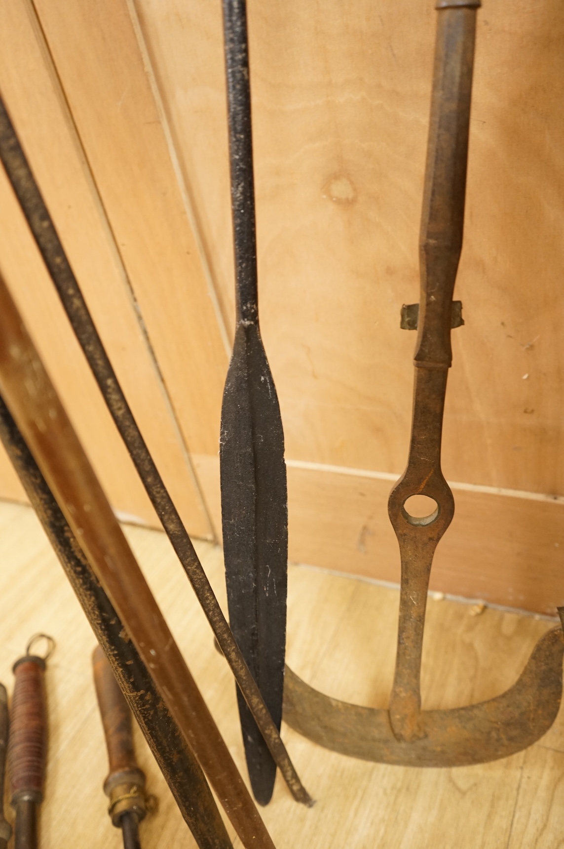 A collection of tribal spears, a fish hook, a cased snooker cue, etc.